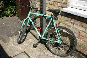 Query photo: a turquoise bicycle against a brick wall